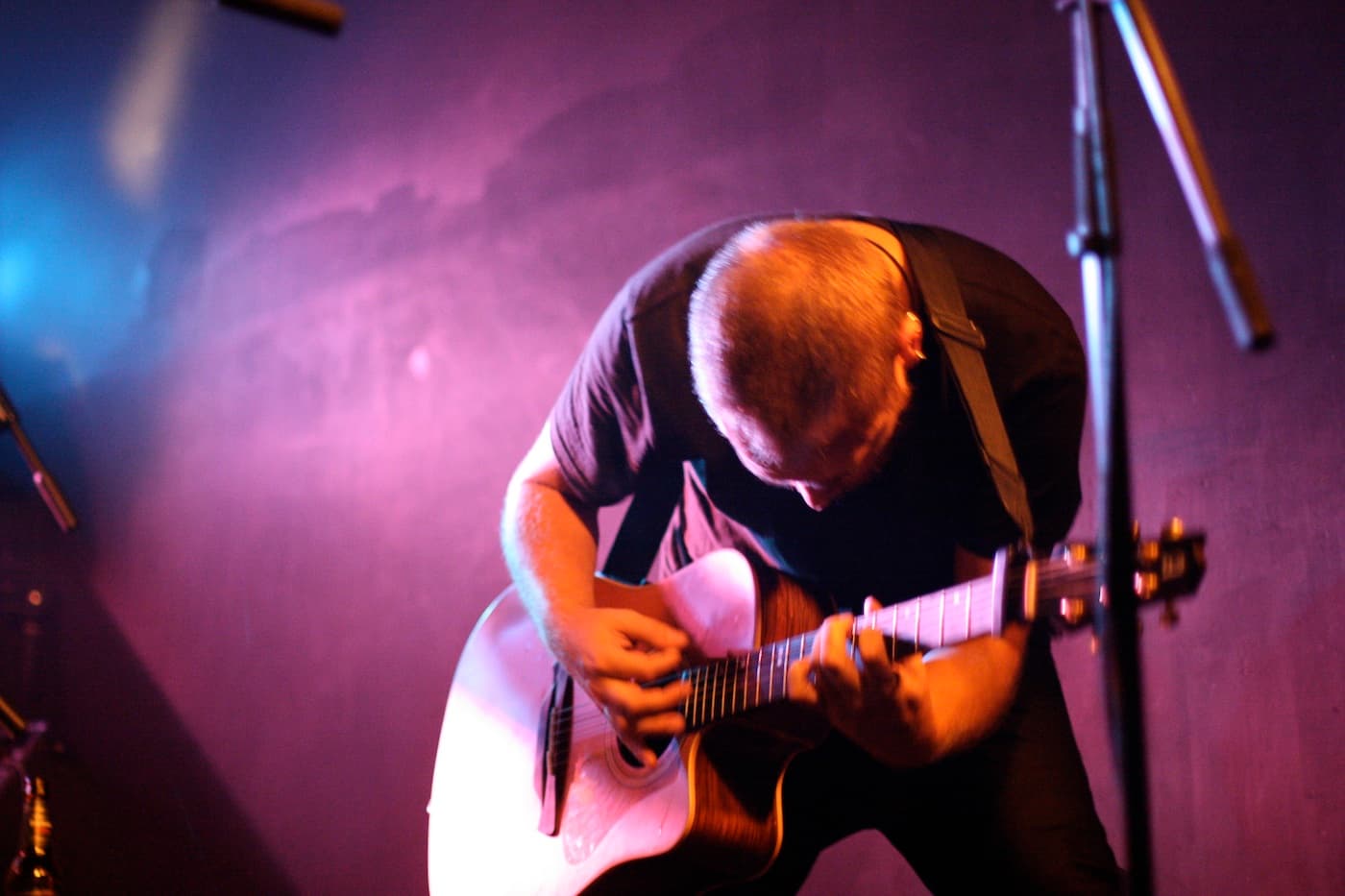 Dani Cabezas tocando la guitarra acústica en directo bajo luz violeta