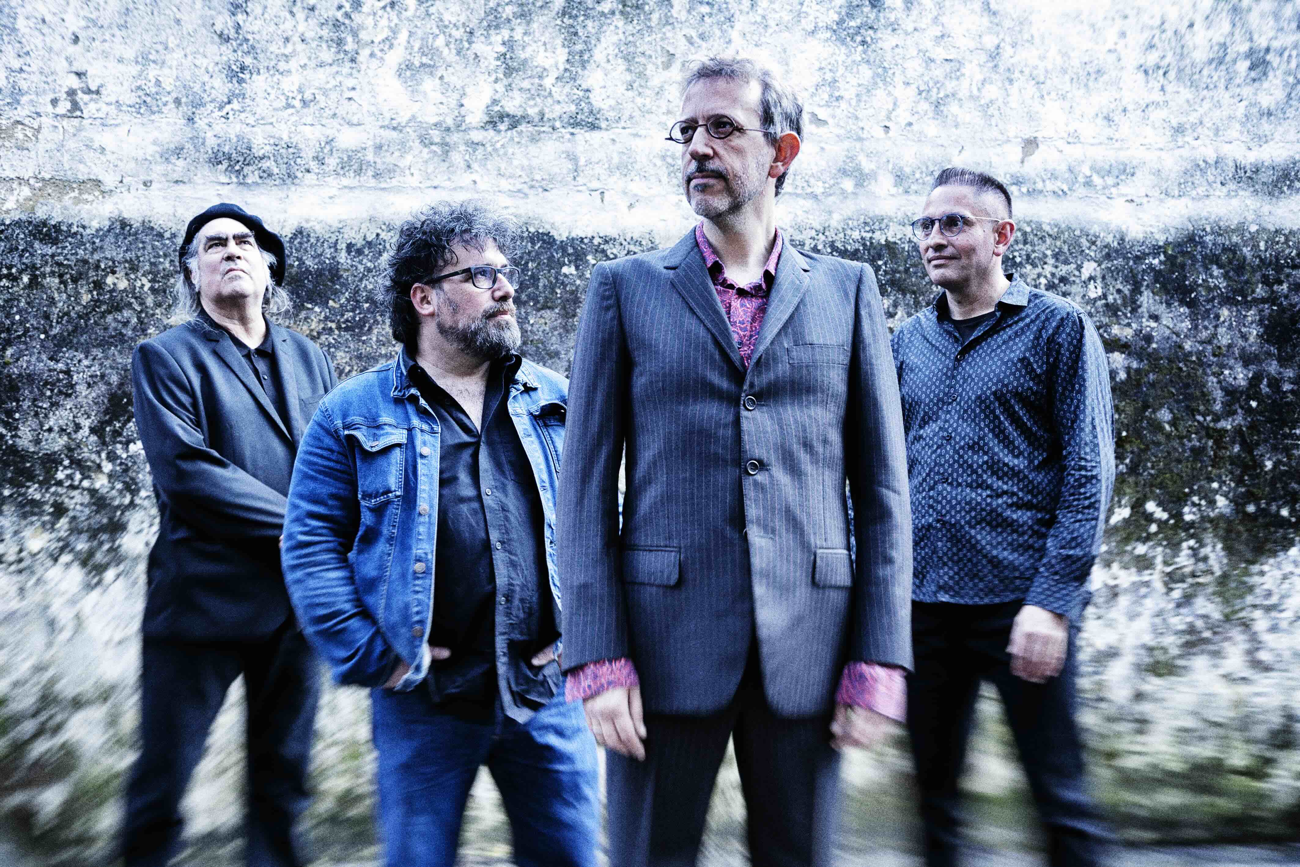 Los cuatro miembros de Stormy Mondays posando delante de un muro de piedra